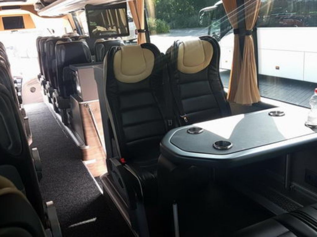 Innenraum des Volvo Premium Busses von Drive 57 Busvermietung, ausgestattet mit bequemen Sitzen und Tischen.